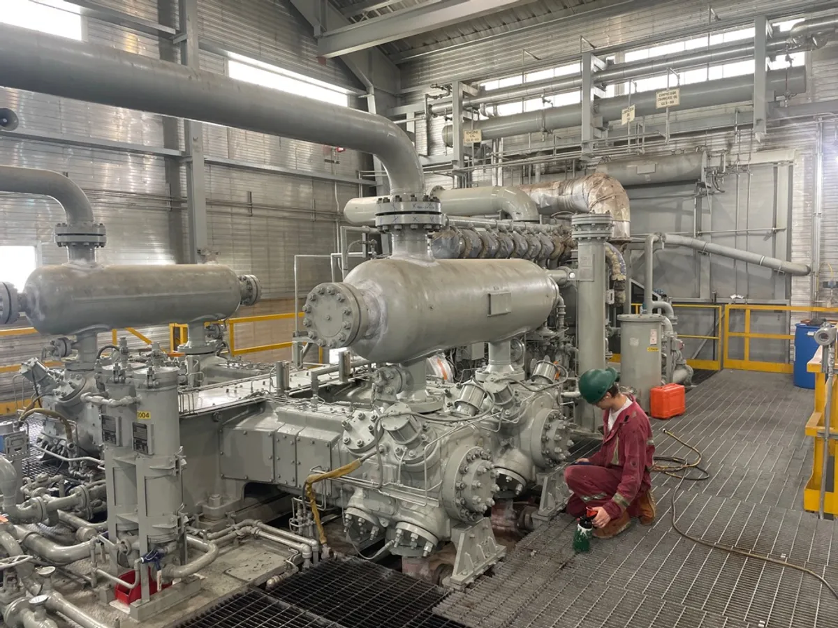 Technician servicing a reciprocating compressor